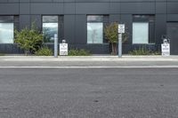 a black suv is parked outside the building next to street signs and trees that are on a sidewalk