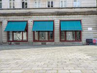 an empty area with two blue awnings outside and no chairs to sit in the front