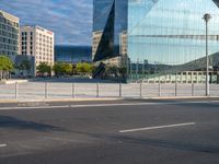 a blue glass office building in a city parking lot with lots of trees around it