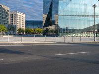 a blue glass office building in a city parking lot with lots of trees around it