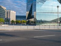 a blue glass office building in a city parking lot with lots of trees around it