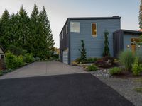 a blue house with a sidewalk leading to it with a garage at the end and some green trees