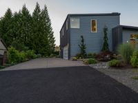 a blue house with a sidewalk leading to it with a garage at the end and some green trees