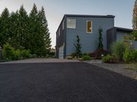 a blue house with a sidewalk leading to it with a garage at the end and some green trees