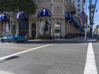 people are walking down the road near a store with blue and white awnings