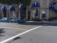 people are walking down the road near a store with blue and white awnings