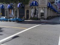 people are walking down the road near a store with blue and white awnings