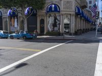 people are walking down the road near a store with blue and white awnings