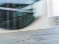 a blurry picture of an outside building with the reflection of a bus passing by