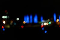 blurred city lights in the dark with bright blue lights reflecting off the buildings in the distance