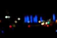 blurred city lights in the dark with bright blue lights reflecting off the buildings in the distance