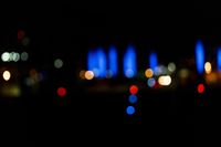 blurred city lights in the dark with bright blue lights reflecting off the buildings in the distance