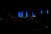 blurred city lights in the dark with bright blue lights reflecting off the buildings in the distance