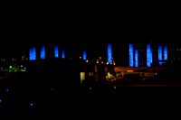 blurred city lights in the dark with bright blue lights reflecting off the buildings in the distance