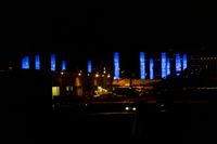 blurred city lights in the dark with bright blue lights reflecting off the buildings in the distance