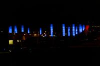 blurred city lights in the dark with bright blue lights reflecting off the buildings in the distance