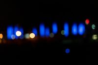 blurred city lights in the dark with bright blue lights reflecting off the buildings in the distance