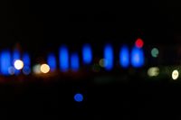 blurred city lights in the dark with bright blue lights reflecting off the buildings in the distance