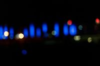 blurred city lights in the dark with bright blue lights reflecting off the buildings in the distance