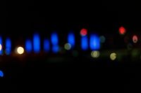 blurred city lights in the dark with bright blue lights reflecting off the buildings in the distance