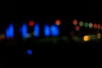 blurred city lights in the dark with bright blue lights reflecting off the buildings in the distance