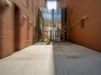 blurred image of a long narrow alleyway with cars passing by it at one end