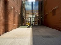 blurred image of a long narrow alleyway with cars passing by it at one end