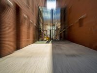 blurred image of a long narrow alleyway with cars passing by it at one end