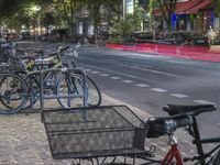 a lot of bicycles are parked along the sidewalk along the road with traffic going by