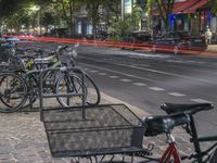 a lot of bicycles are parked along the sidewalk along the road with traffic going by