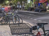 a lot of bicycles are parked along the sidewalk along the road with traffic going by