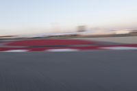 a blurry photo of a motorcycle racing down a racetrack with an airplane in the background