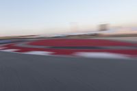 a blurry photo of a motorcycle racing down a racetrack with an airplane in the background