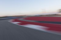 a blurry photo of a motorcycle racing down a racetrack with an airplane in the background