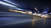 a blurry image of a long highway at night with light streaks coming from the cars headlights