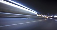 a blurry image of a long highway at night with light streaks coming from the cars headlights