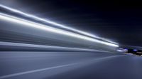a blurry image of a long highway at night with light streaks coming from the cars headlights