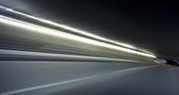 a blurry image of a long highway at night with light streaks coming from the cars headlights