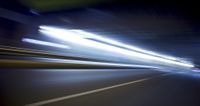 a blurry image of a long highway at night with light streaks coming from the cars headlights