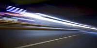 a blurry image of a long highway at night with light streaks coming from the cars headlights