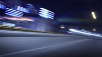 a blurry image of a long highway at night with light streaks coming from the cars headlights