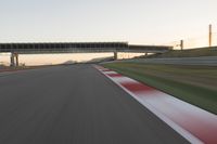 a blurry photo of a speed racing track with an overpass and bridge in the background