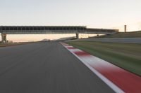 a blurry photo of a speed racing track with an overpass and bridge in the background