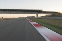 a blurry photo of a speed racing track with an overpass and bridge in the background