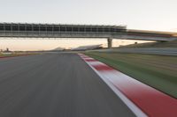 a blurry photo of a speed racing track with an overpass and bridge in the background