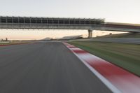 a blurry photo of a speed racing track with an overpass and bridge in the background