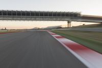 a blurry photo of a speed racing track with an overpass and bridge in the background