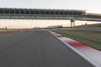 a blurry photo of a speed racing track with an overpass and bridge in the background