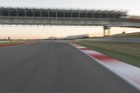 a blurry photo of a speed racing track with an overpass and bridge in the background