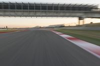 a blurry photo of a speed racing track with an overpass and bridge in the background